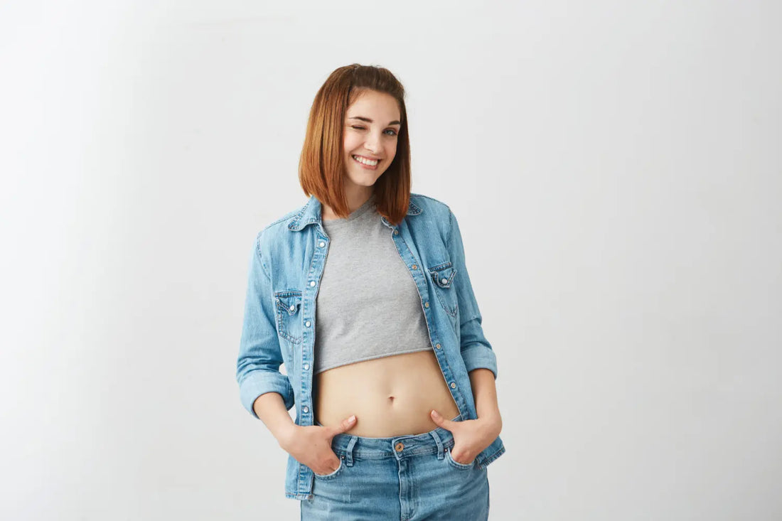 Uma jovem mulher está em forma sem gordura localizada na barriga