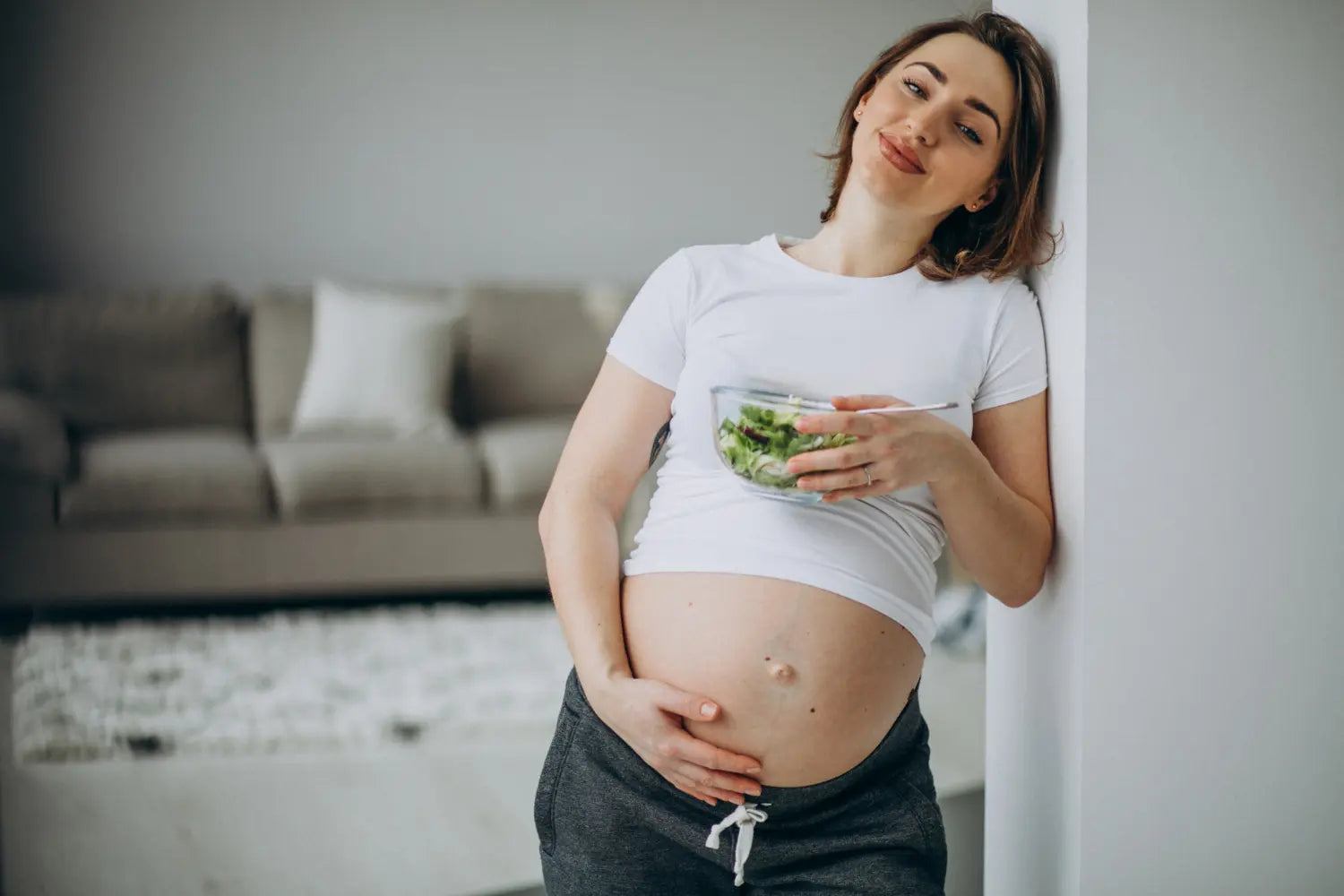 Uma jovem come salada com vitamina para gestante